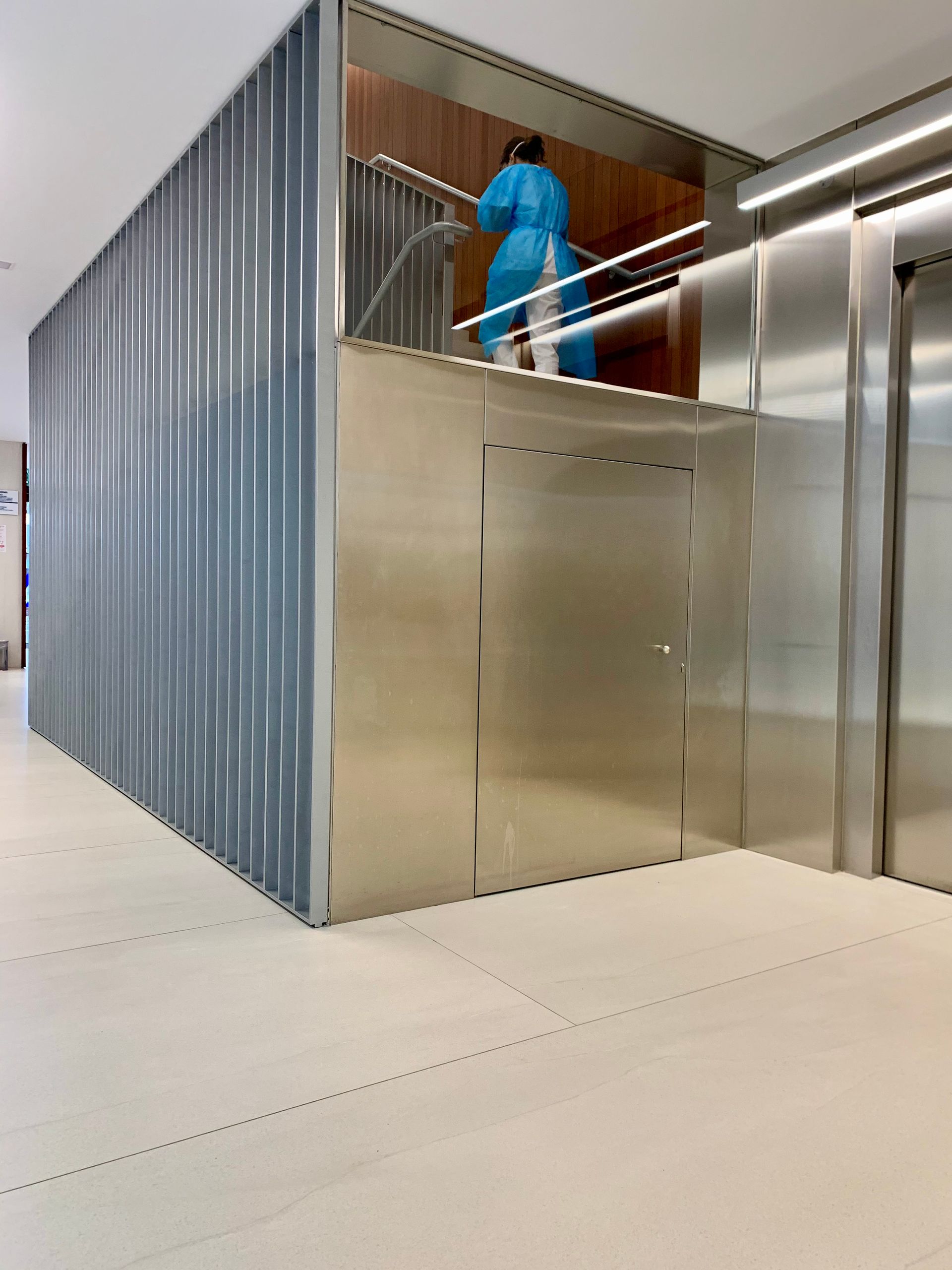 Una mujer con una túnica azul baja las escaleras de un edificio.