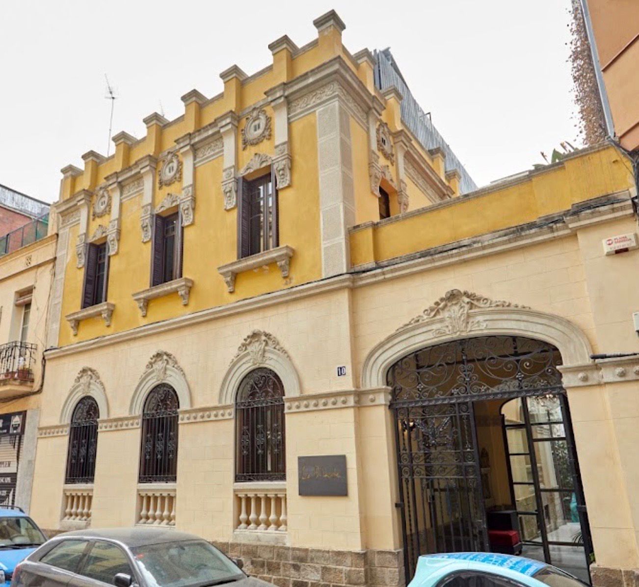 Un edificio amarillo con coches aparcados delante.