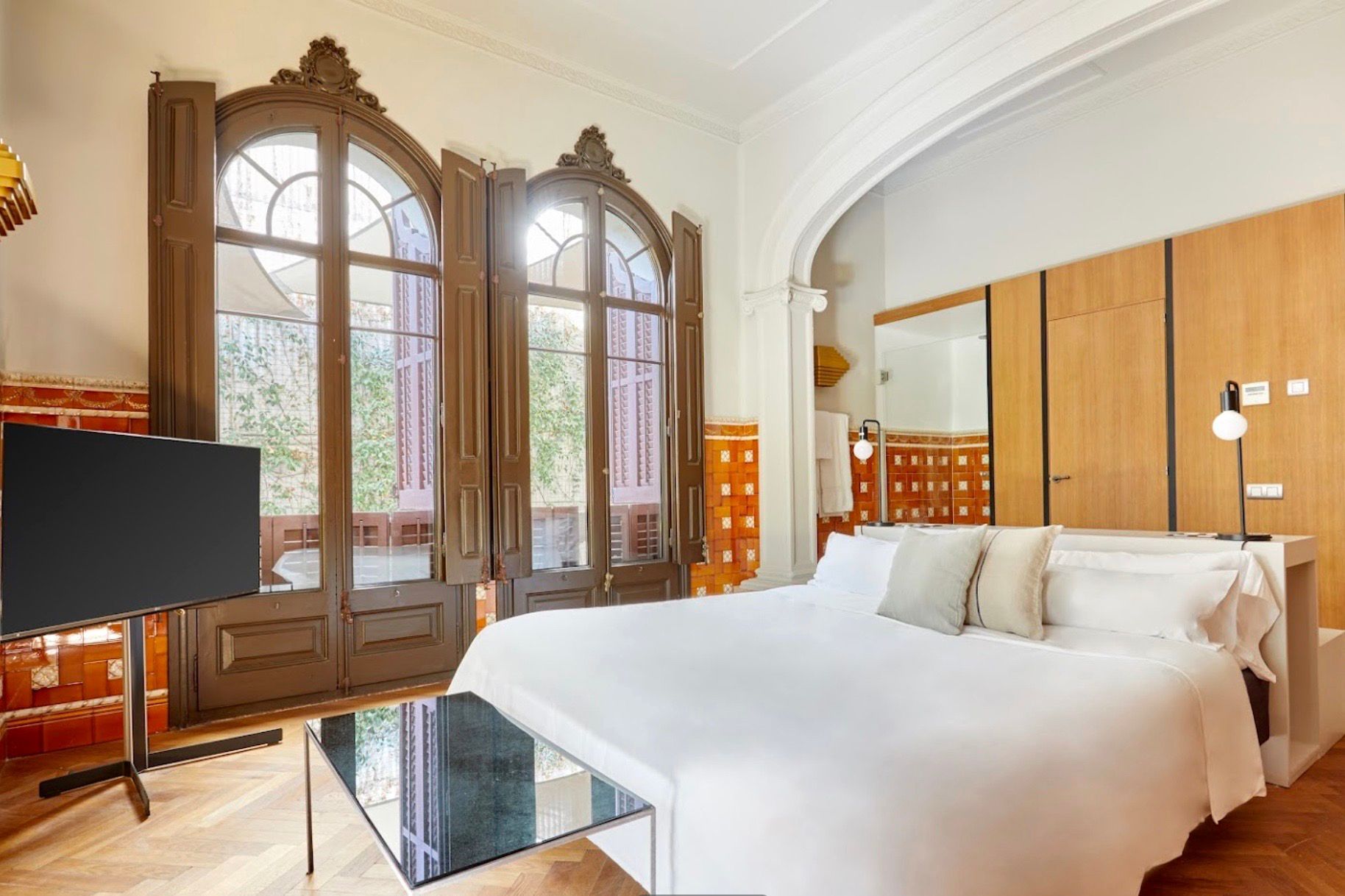 Un dormitorio con una cama king size, televisión y grandes ventanales.