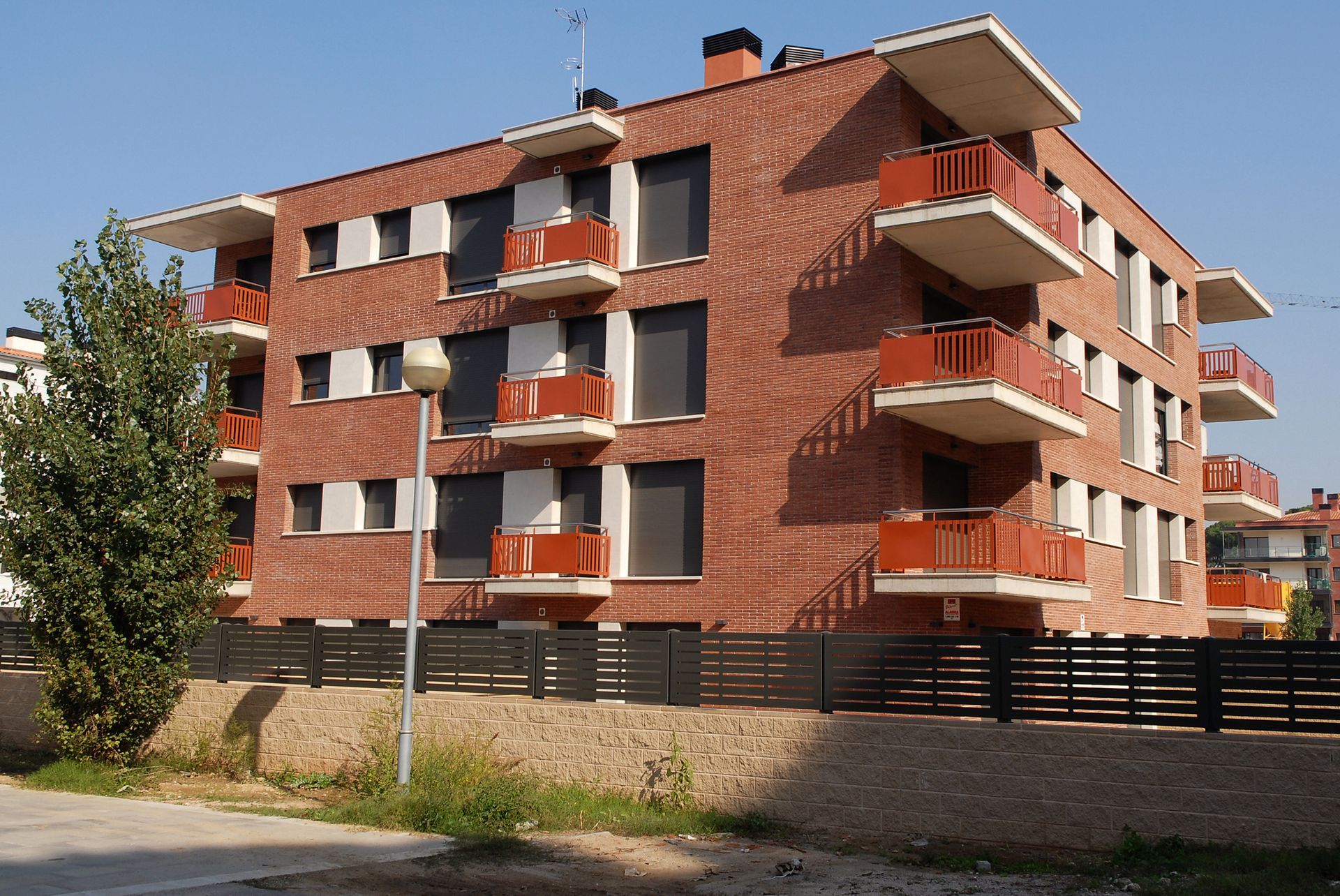 Un gran edificio de apartamentos de ladrillo con balcones naranjas.