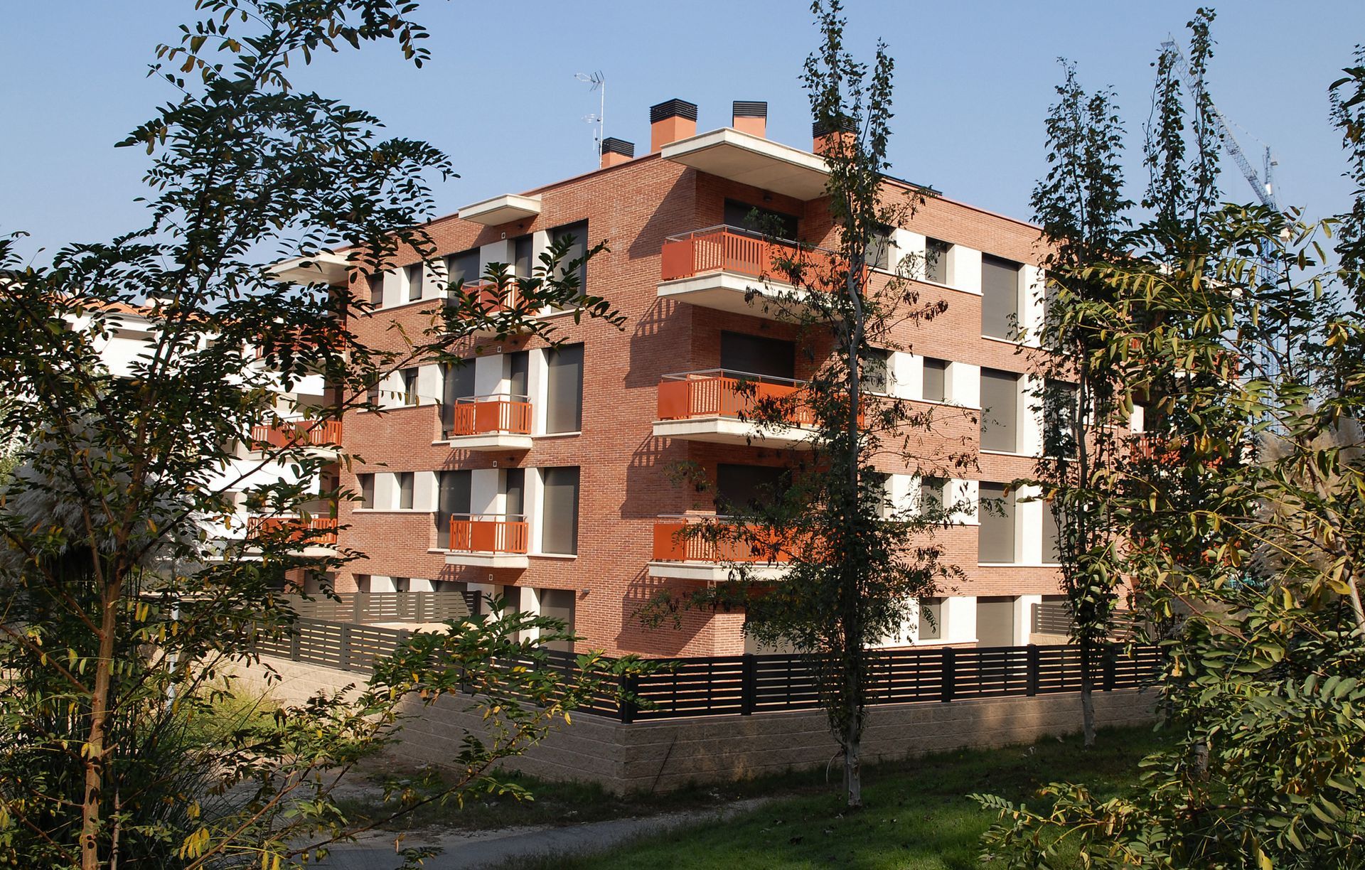 Un edificio de apartamentos de ladrillo con balcones y árboles en el frente.