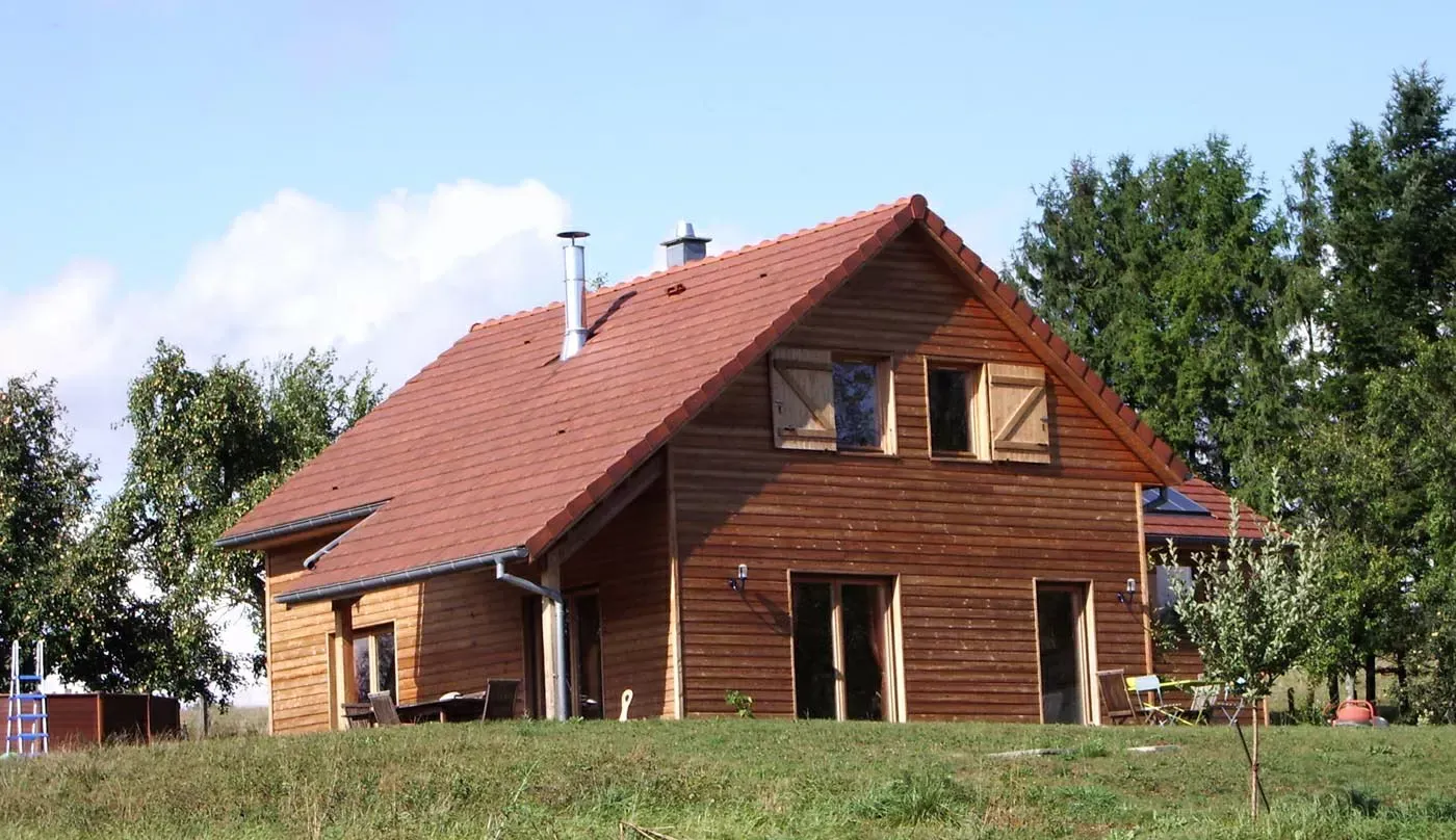 Maison en briques au toit rouge sur un terrain herbeux sous un ciel bleu