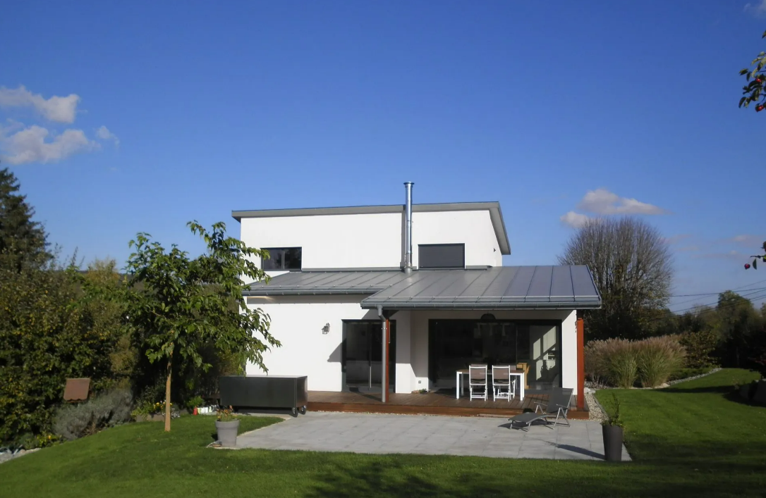 Maison blanche à deux étages avec patio et pelouse sous un ciel bleu clair