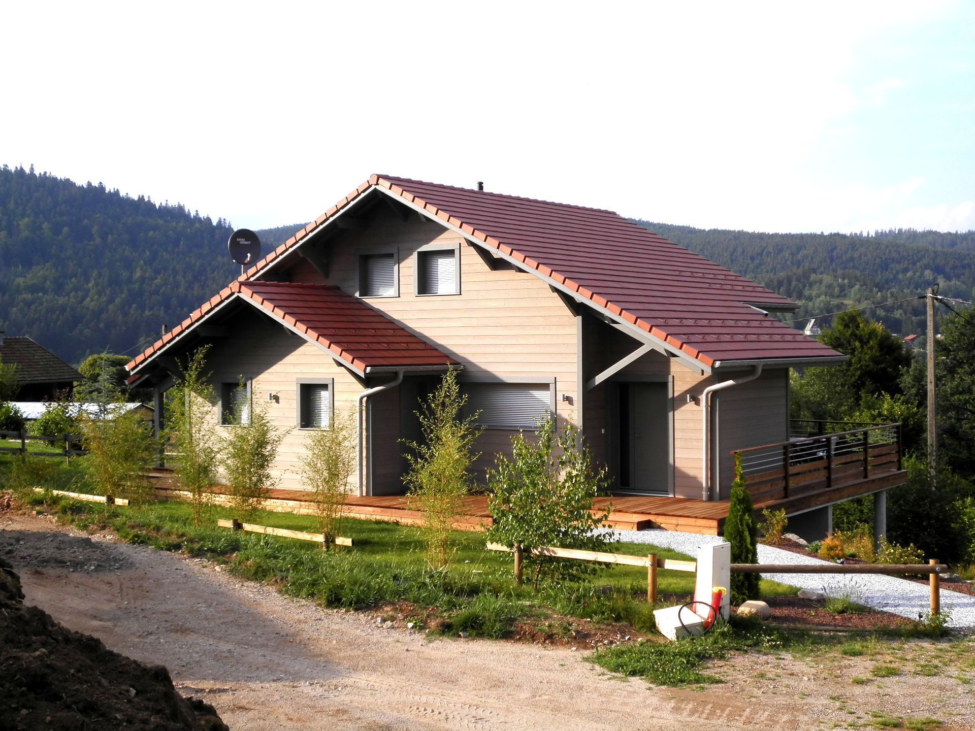 Maison au toit rouge dans un paysage rural, avec des montagnes en arrière-plan