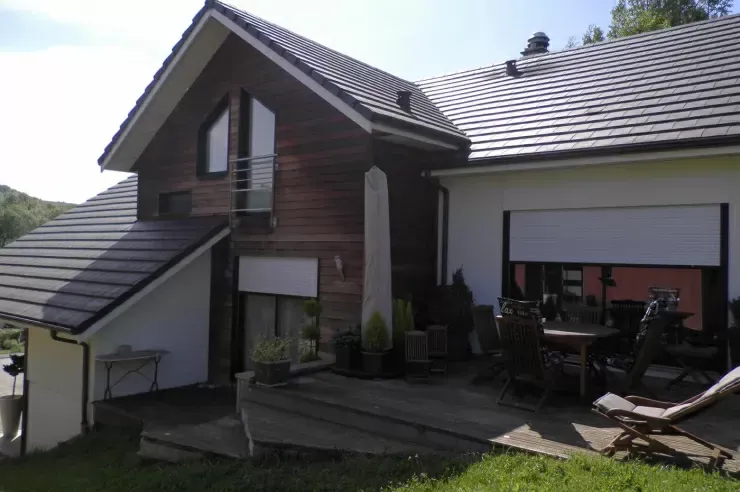 Extérieur de maison moderne avec un toit en pente, mobilier de patio et pelouse ensoleillée