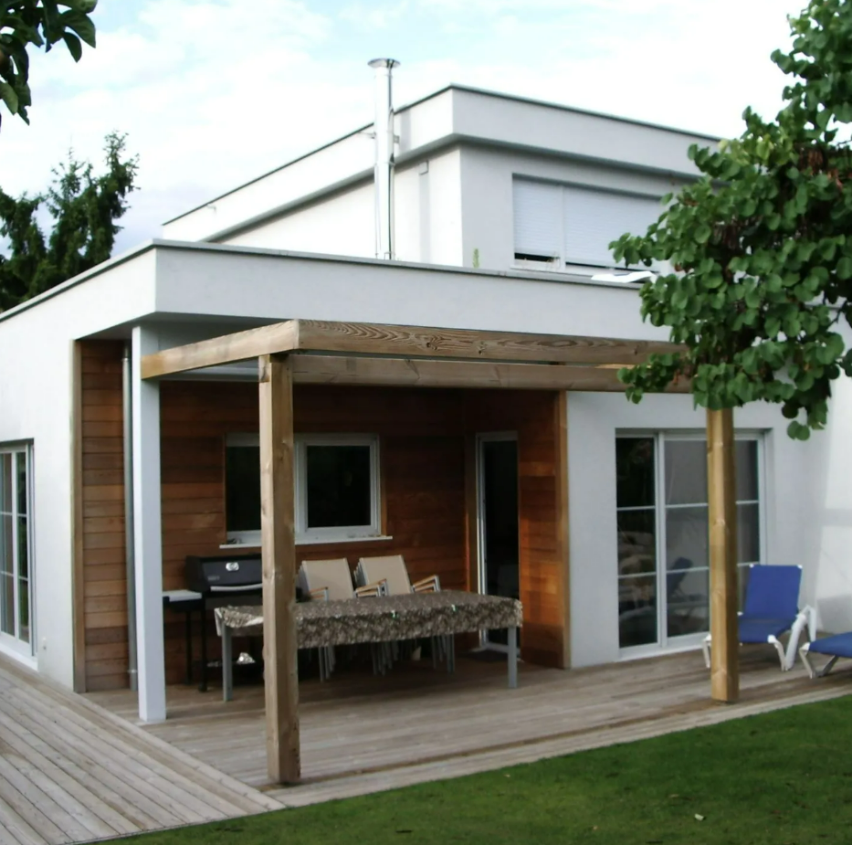 Maison blanche moderne avec terrasse en bois, patio couvert, table à manger extérieure et chaises longues