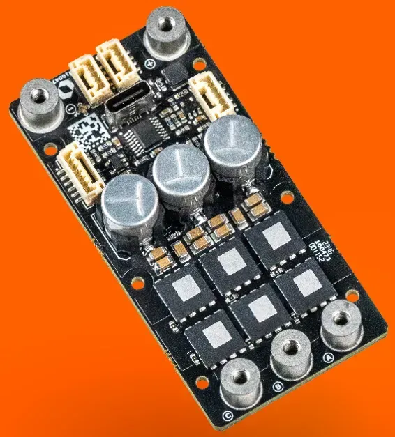 Eine schwarze, rechteckige Leiterplatte mit Metallabstandshaltern, einem USB-C-Anschluss, drei runden Kondensatoren und mehreren elektronischen Chips.