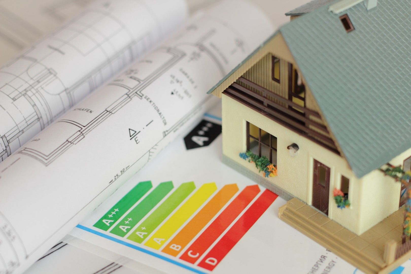 Maquette de maison sur un graphique d’efficacité énergétique, à côté de plans architecturaux