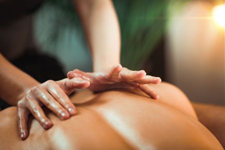 Une personne prodigue un massage du dos sur une personne allongée.