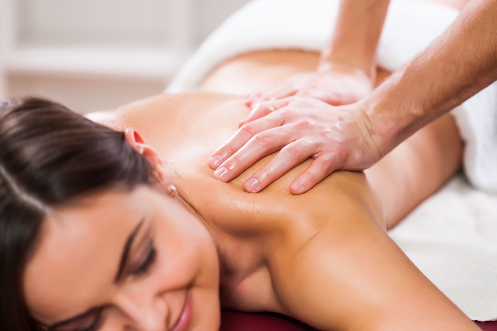 Une masseuse effectue un massage du dos sur une femme allongée sur le ventre sur une table.