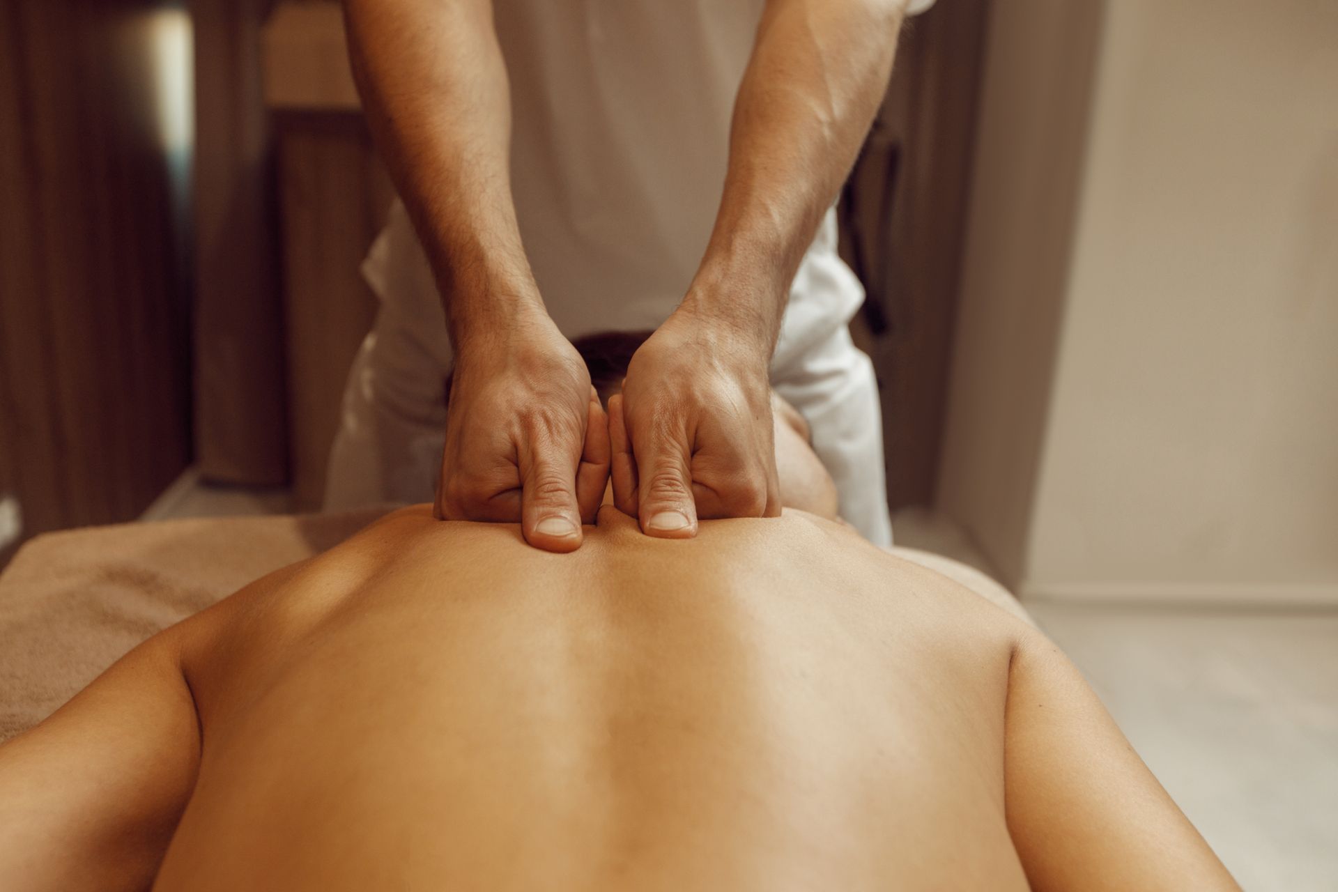 Un masseur masse le dos d'une personne sur une table de massage.