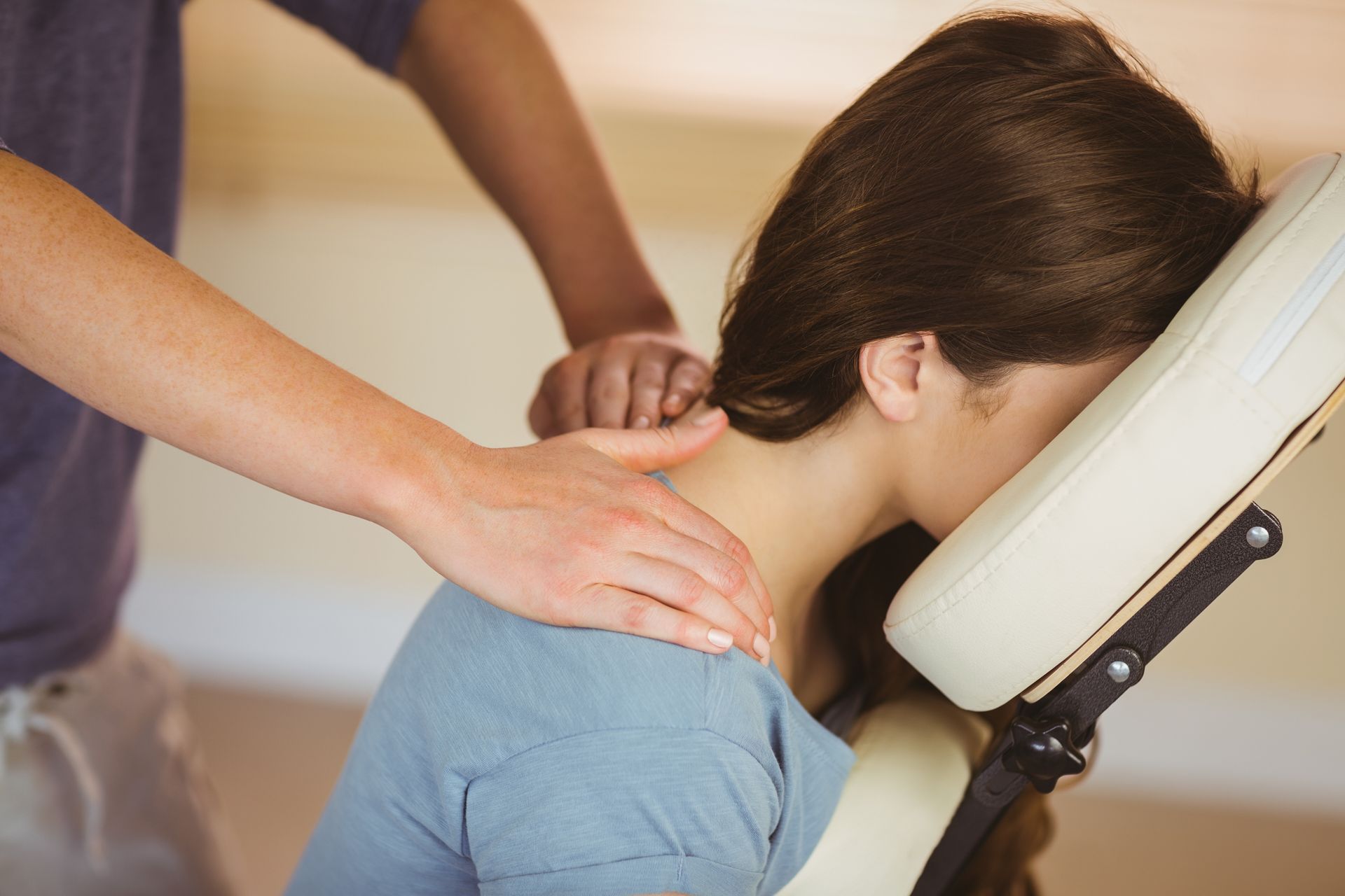 Un massothérapeute travaille sur la nuque et les épaules d'une personne assise sur un fauteuil de massage.