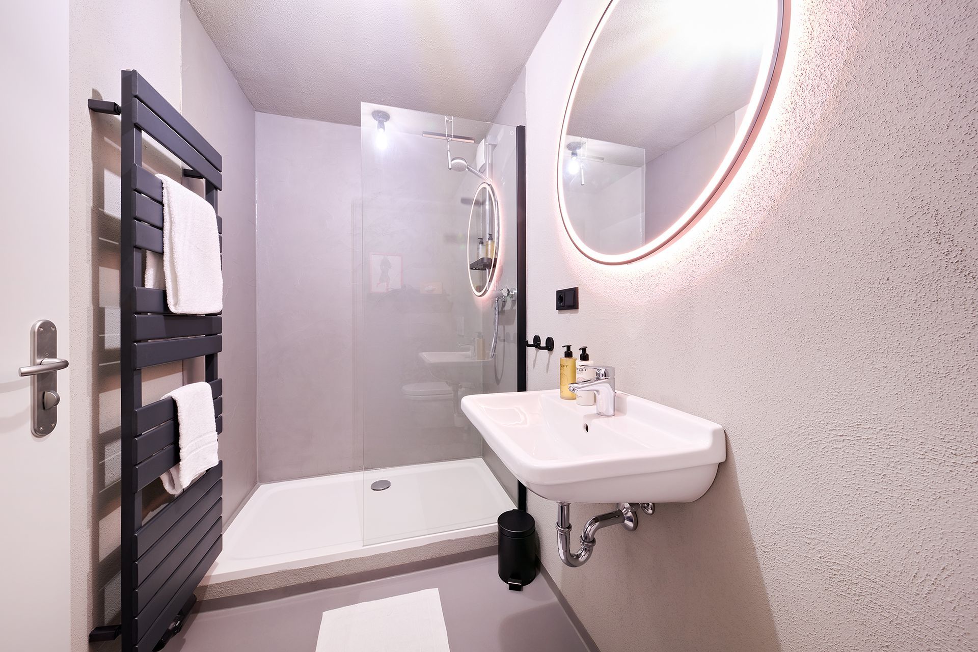 Ein Badezimmer mit Waschbecken, Spiegel und ebenerdiger Dusche.