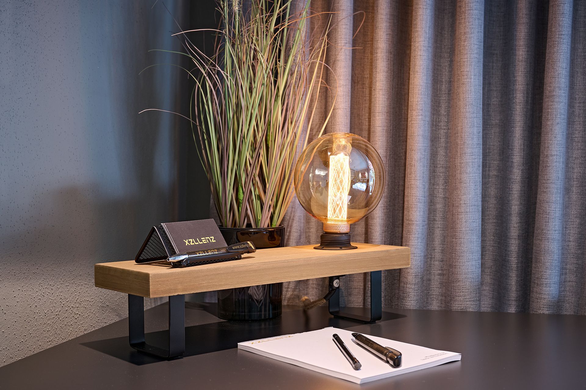 Ein Schreibtisch mit einer Lampe und einem Notizbuch darauf.