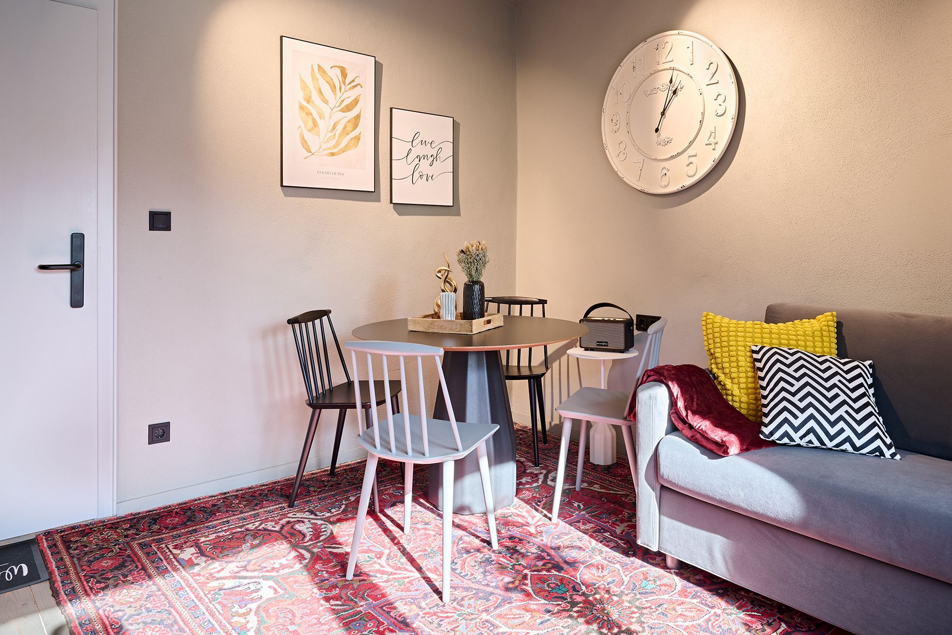 Ein Wohnzimmer mit Sofa, Tisch und Stühlen und einer Uhr an der Wand.