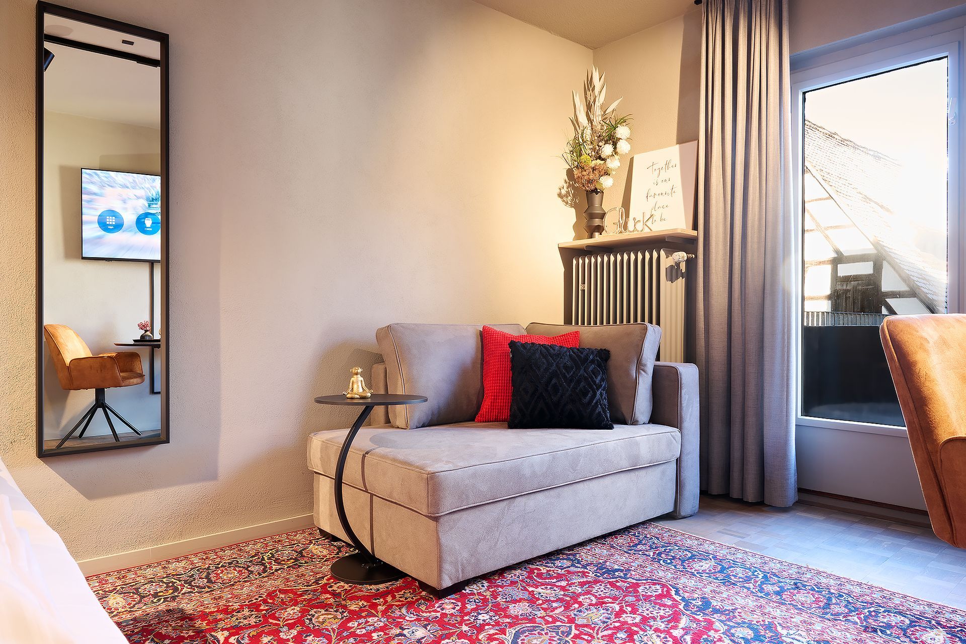Ein Wohnzimmer mit Couch, Teppich, Spiegel und Fernseher.