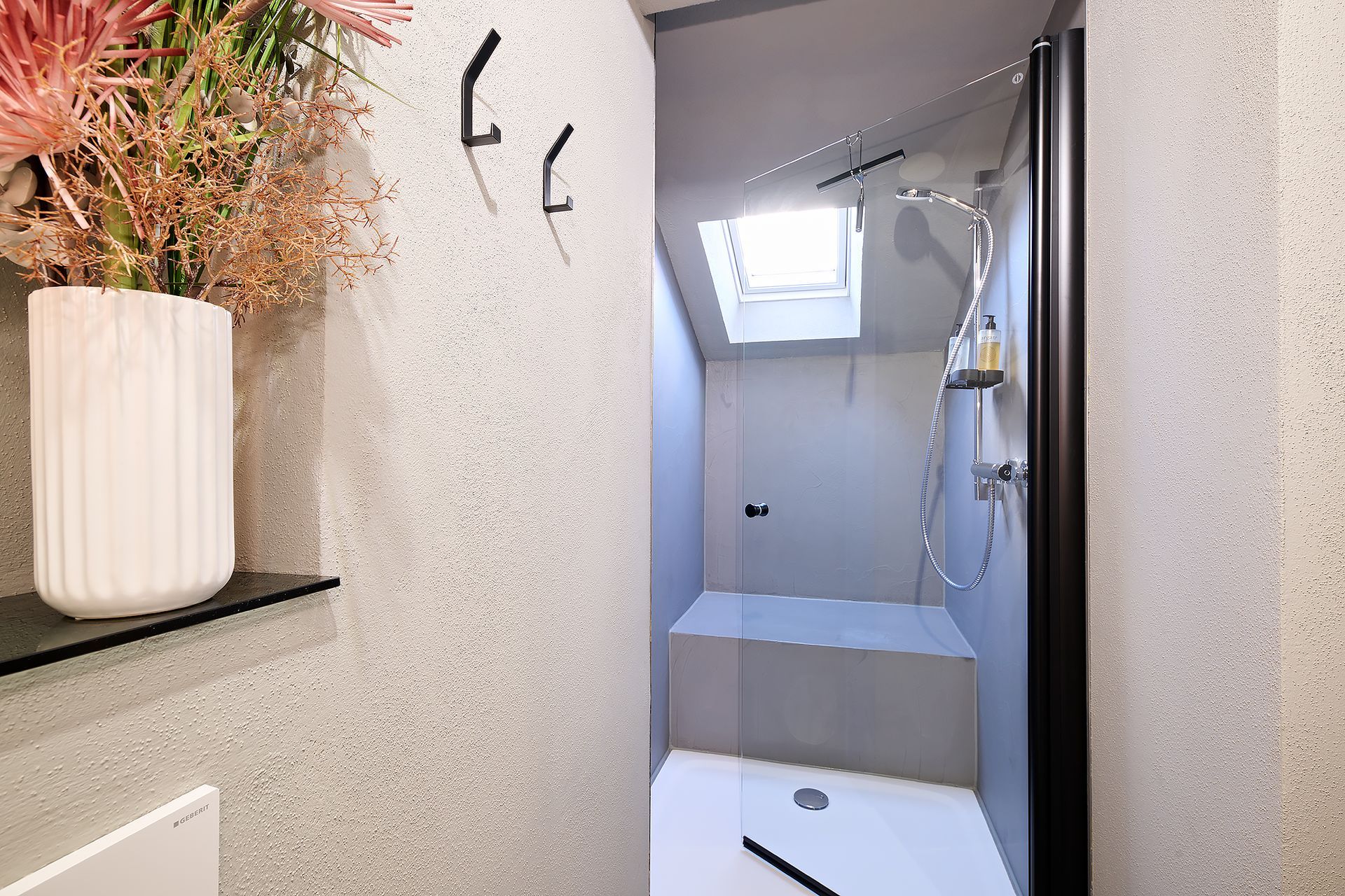 Ein Badezimmer mit Dusche und einer Blumenvase an der Wand.