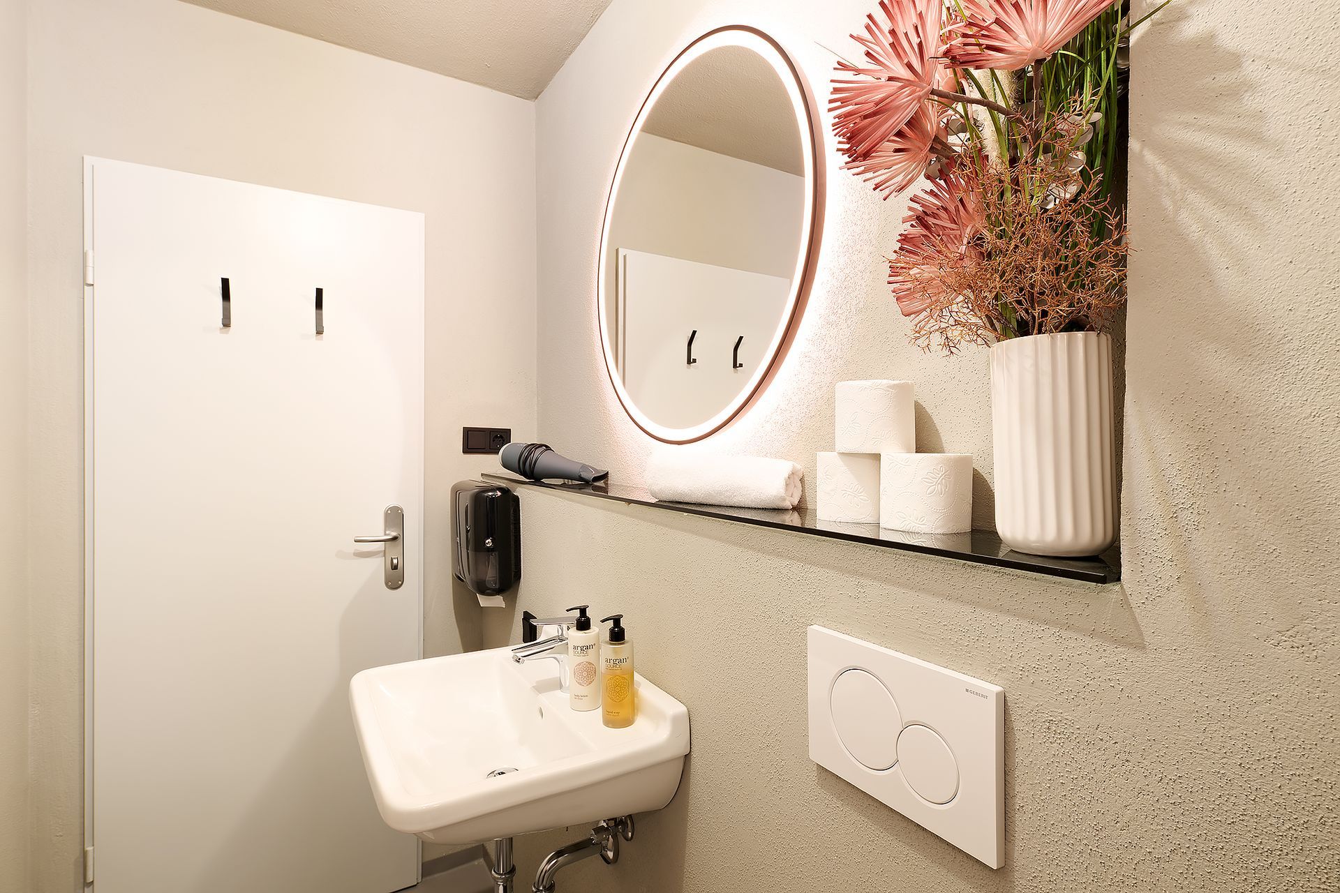 Ein Badezimmer mit Waschbecken, Spiegel und Blumen an der Wand.