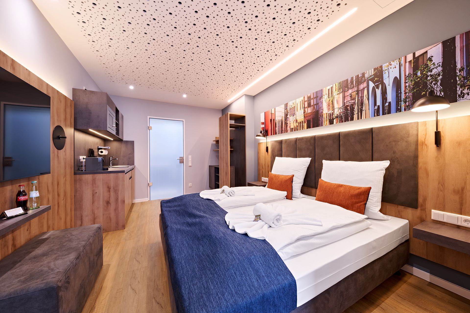 Ein Hotelzimmer mit zwei Betten, einem Fernseher und einer Küche.