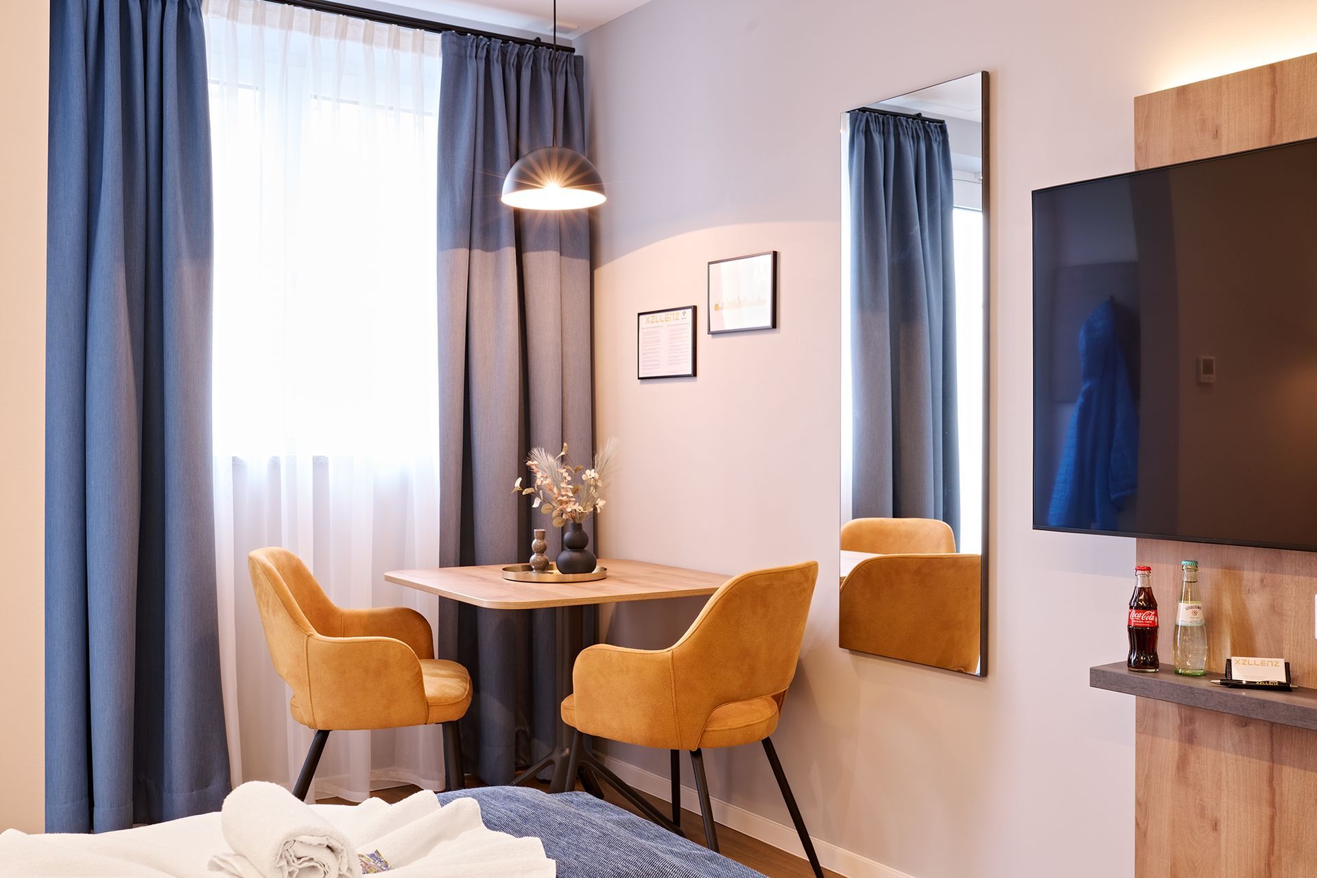 Ein Hotelzimmer mit Bett, Schreibtisch, Stühlen, Fernseher und Spiegel.
