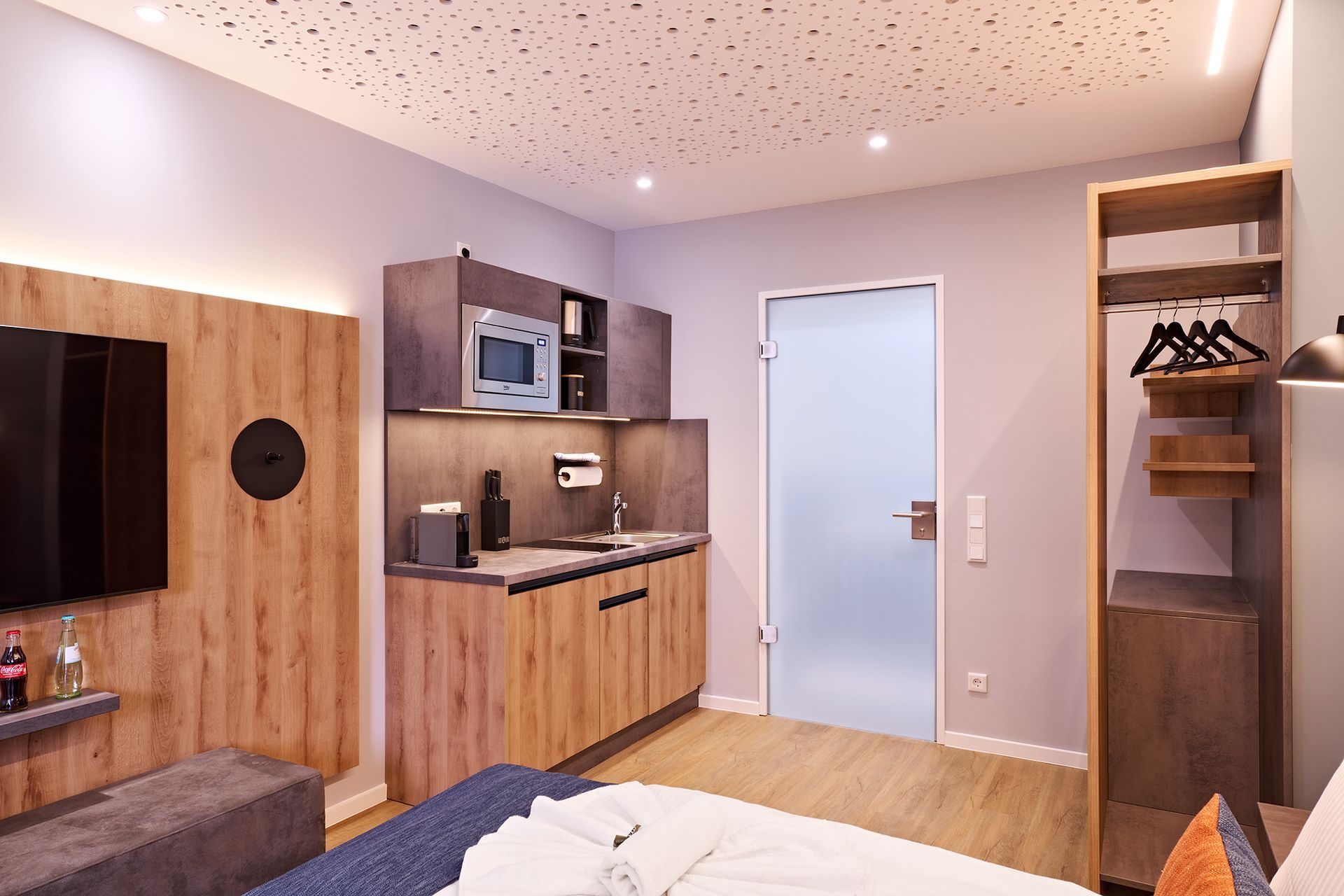 Ein Hotelzimmer mit Bett, Küche und Fernseher.