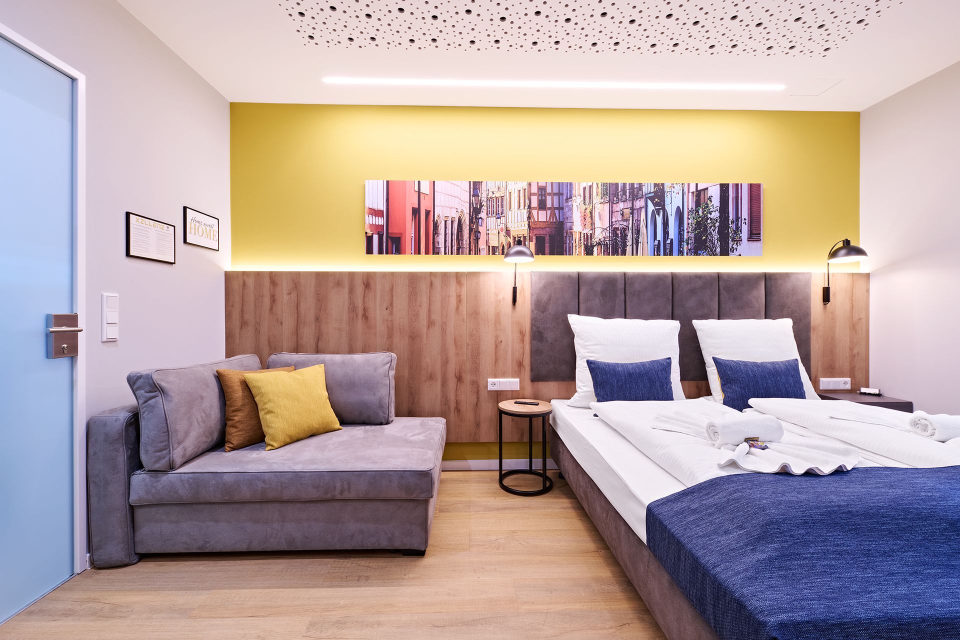 Ein Hotelzimmer mit Bett, Couch und Gemälde an der Wand.