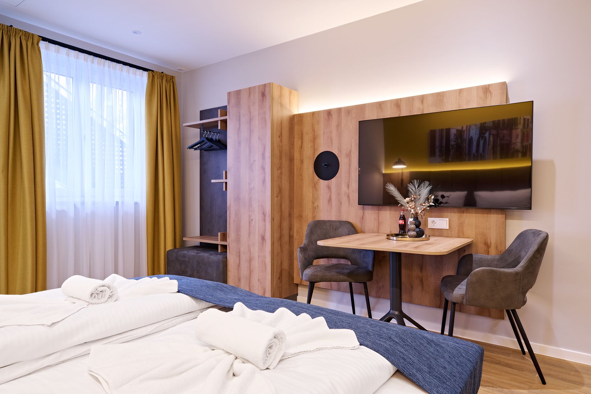 Ein Hotelzimmer mit Bett, Tisch, Stühlen und Fernseher.
