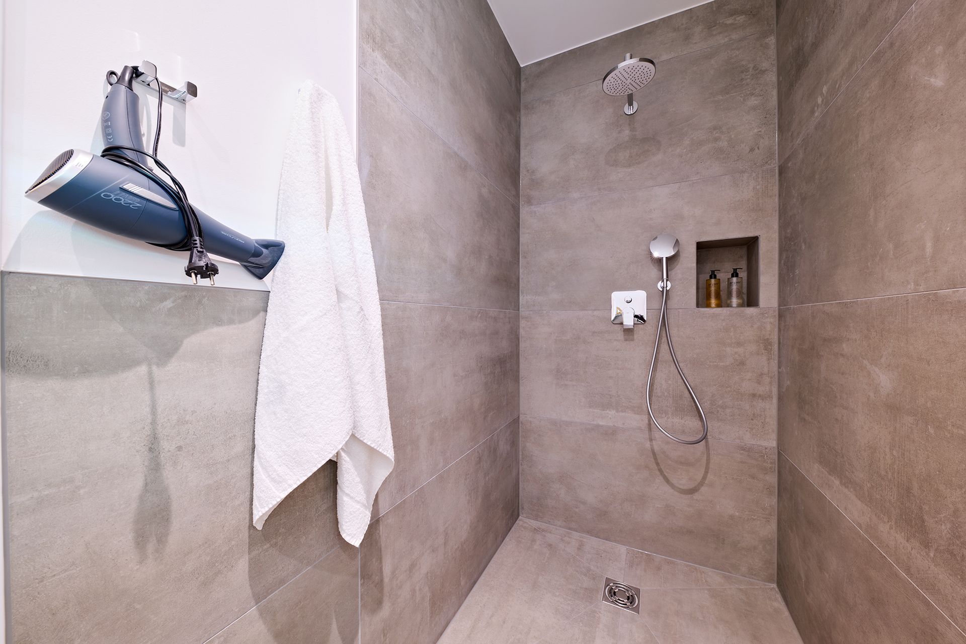 Ein Badezimmer mit Dusche und einem an der Wand hängenden Haartrockner