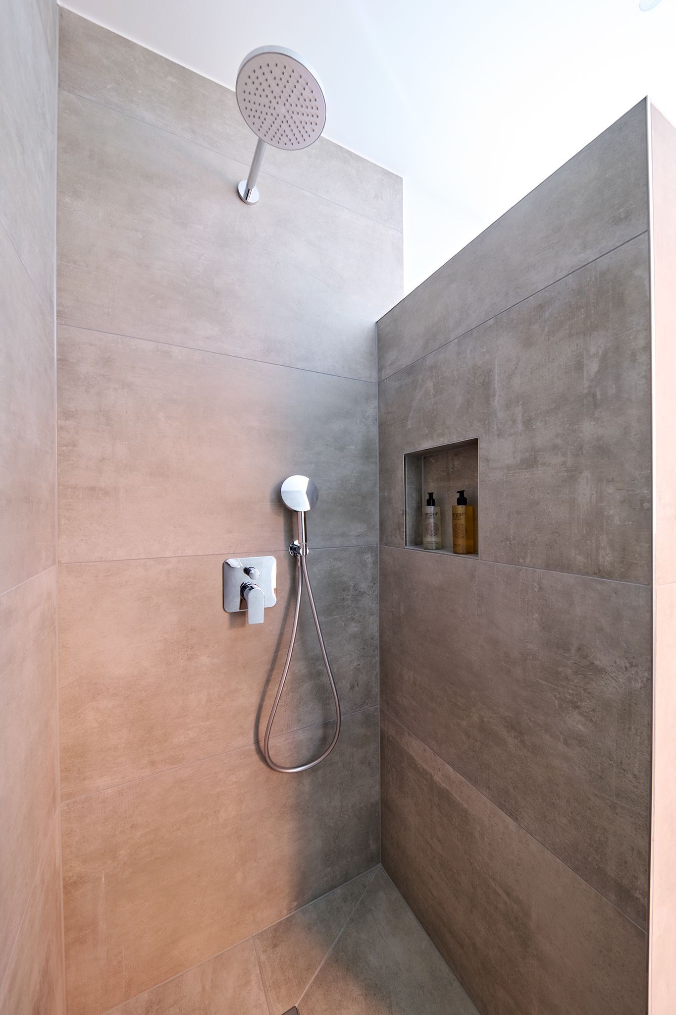 Eine Dusche mit Duschkopf und Seifenspender an der Wand.