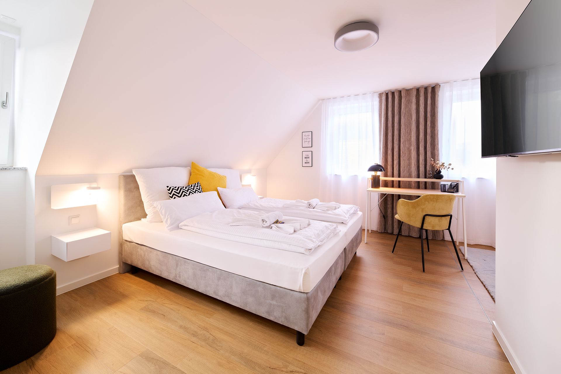 Ein Hotelzimmer mit Bett, Schreibtisch und Fernseher.