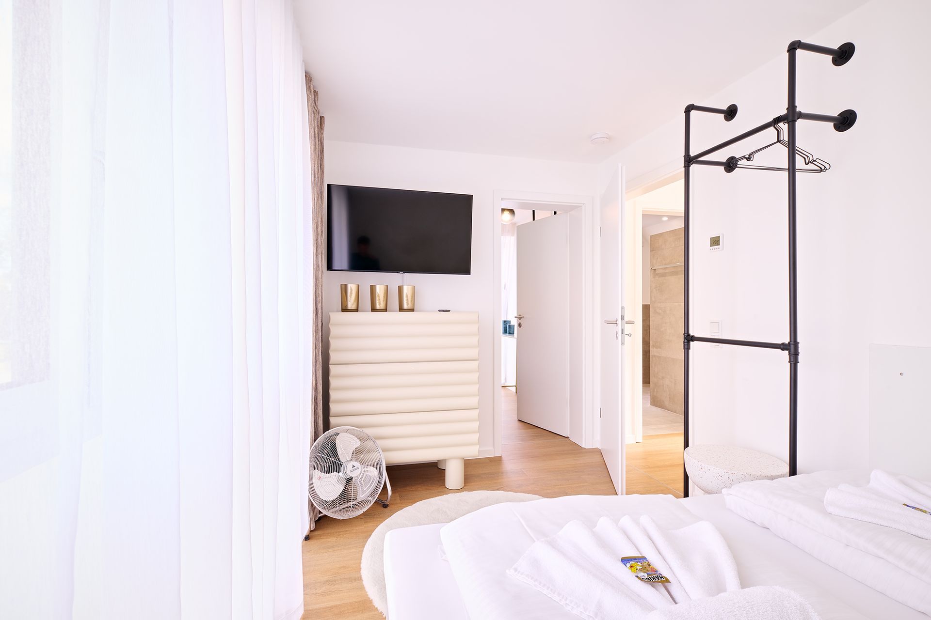 Ein Schlafzimmer mit Bett, Fernseher, Kommode und Garderobe.