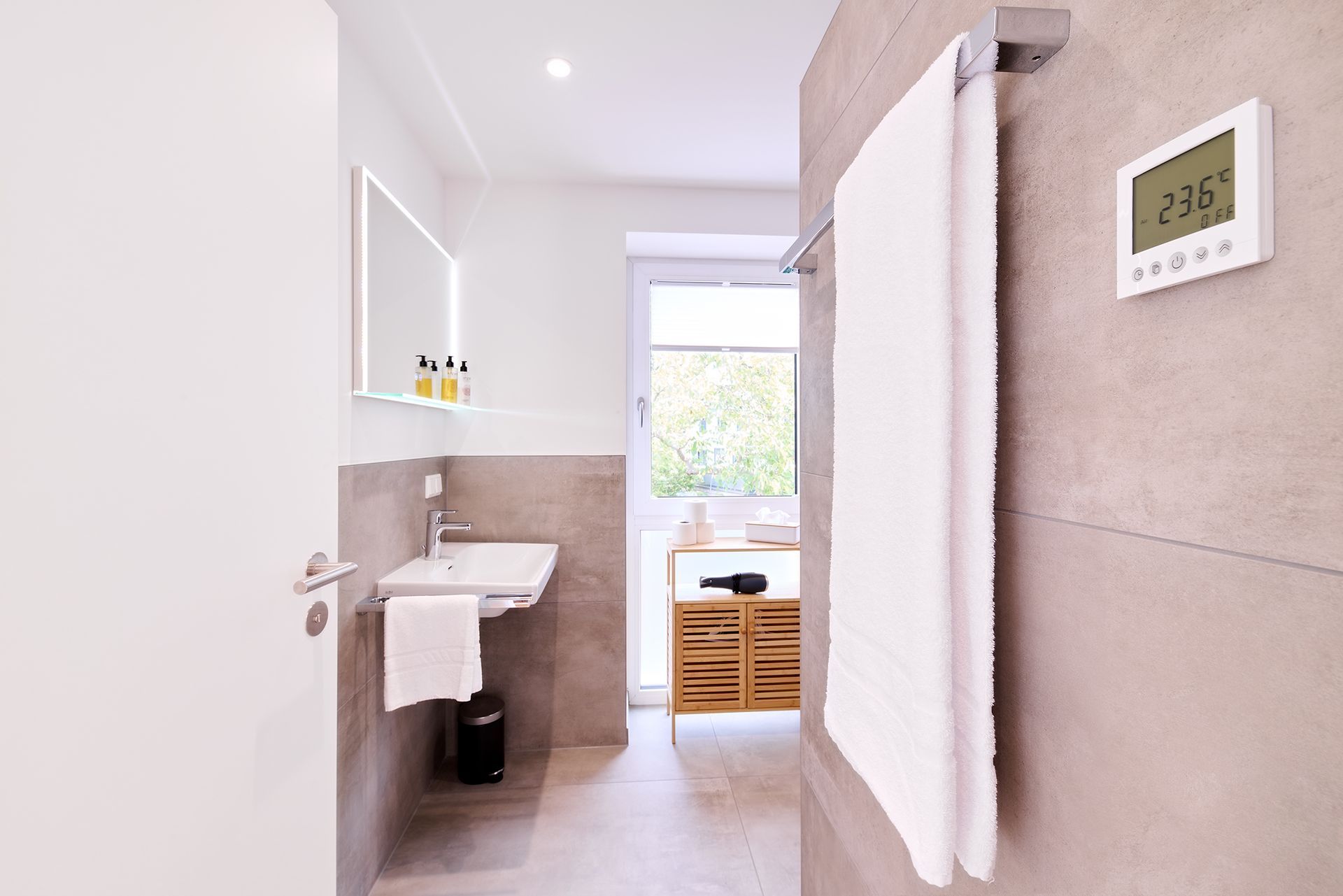 Ein Badezimmer mit Waschbecken und Thermostat an der Wand.