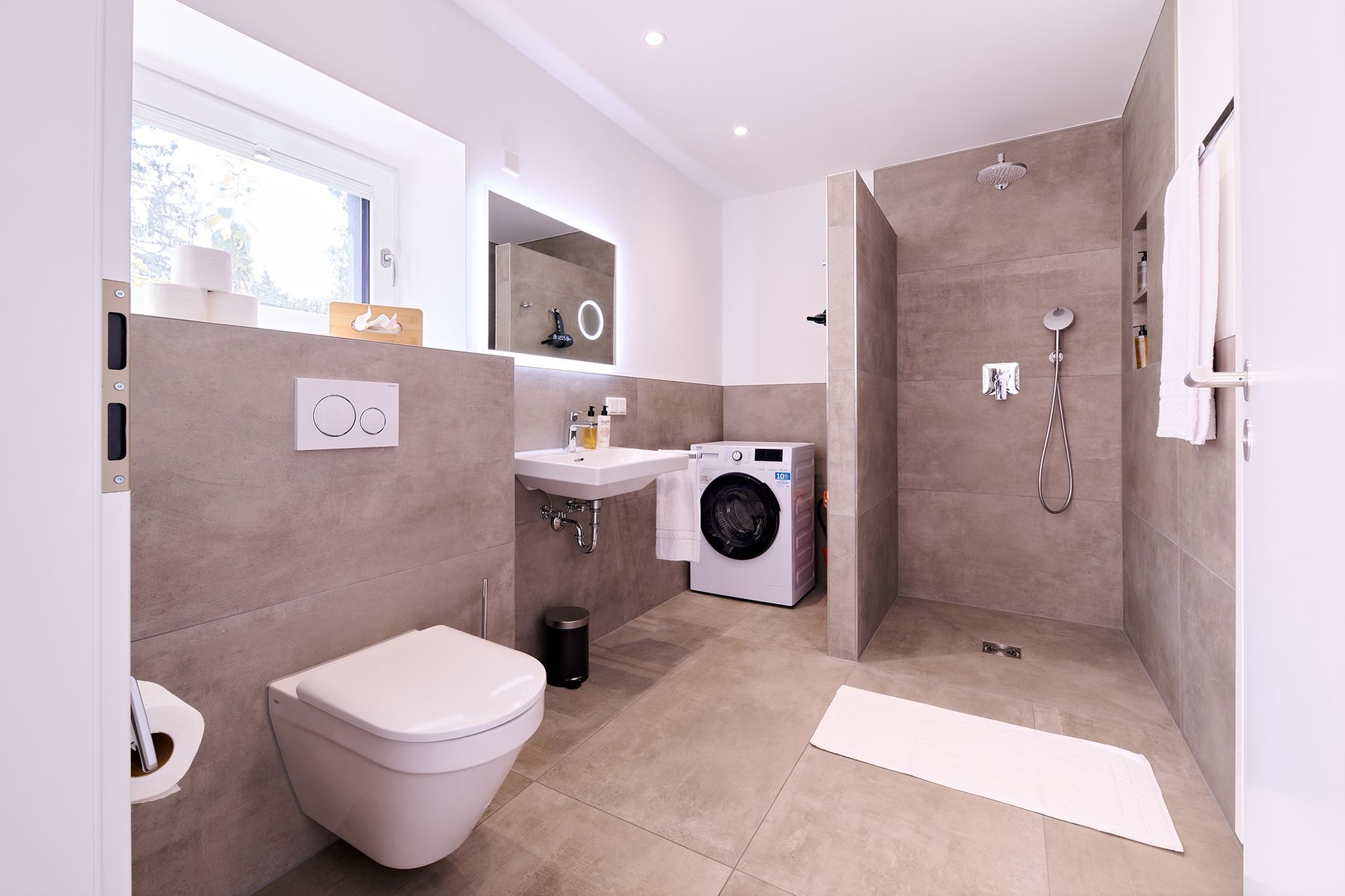 Ein Badezimmer mit Toilette, Waschbecken, Waschmaschine und Trockner.