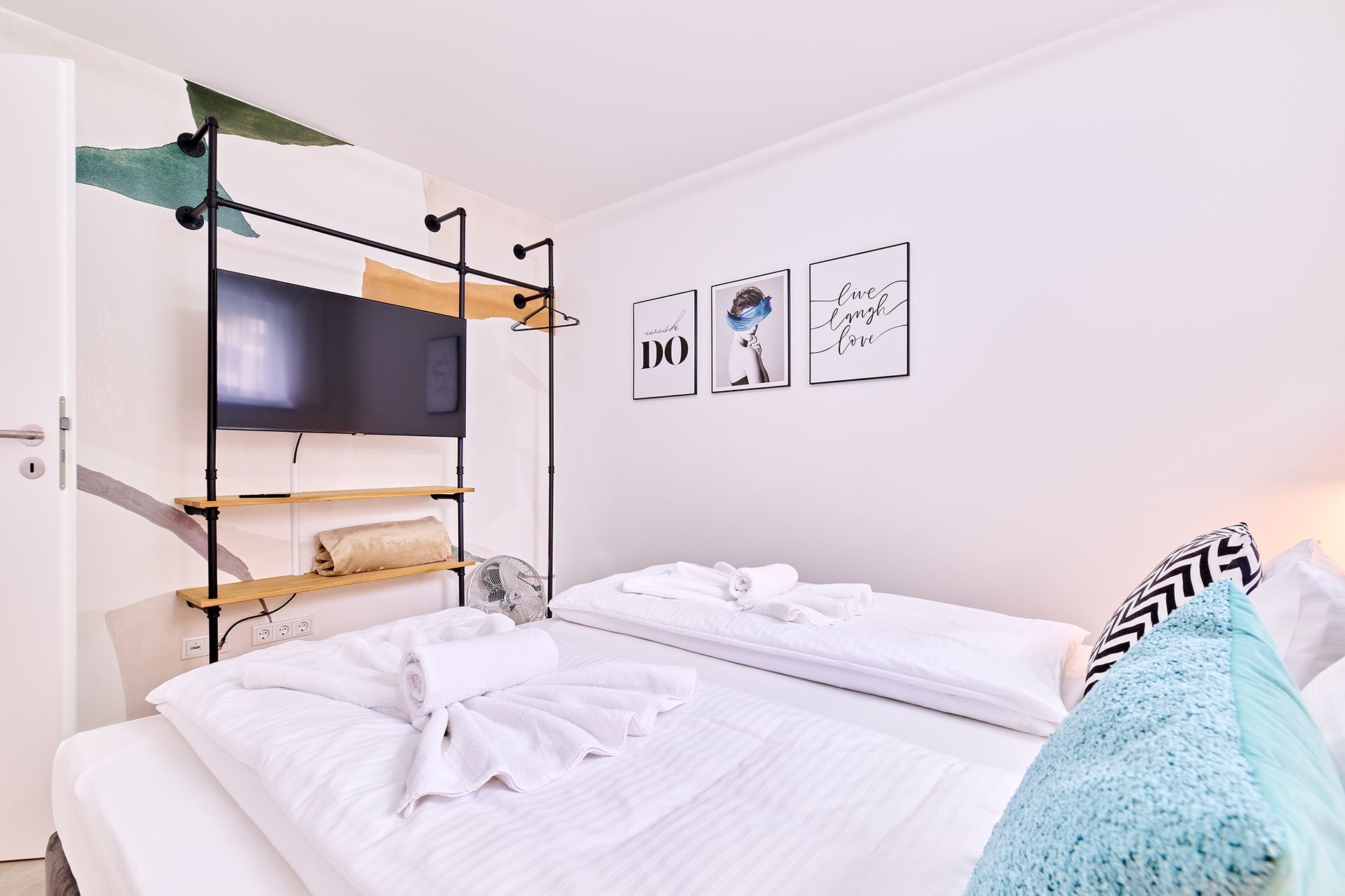 Ein Schlafzimmer mit zwei Betten, einem Fernseher und einem Gemälde an der Wand.