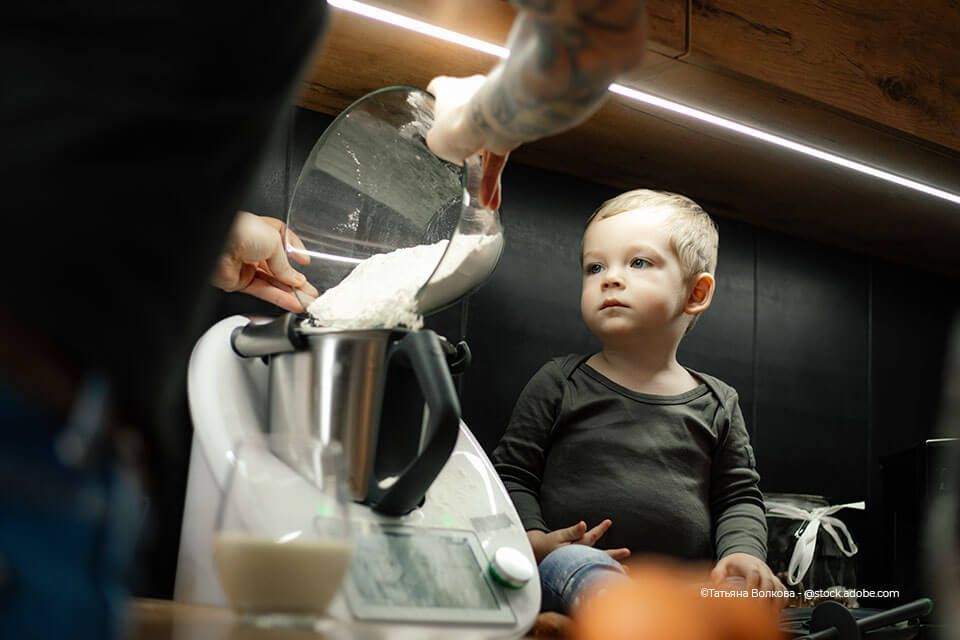 Kind schaut Mutter beim Kochen mit dem Thermomix zu