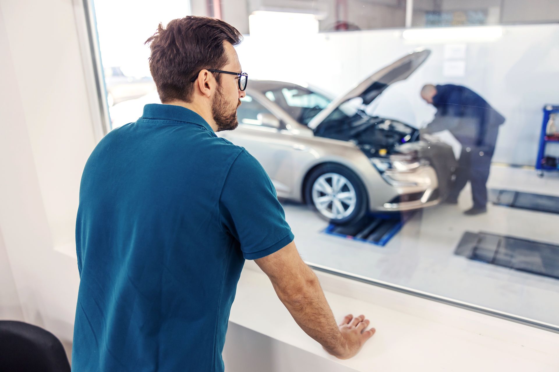 Particulier regardant depuis une vitre le professionnel réaliser le contrôle de sa voiture