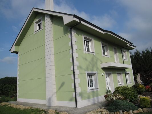 Una casa verde con molduras blancas y chimenea.