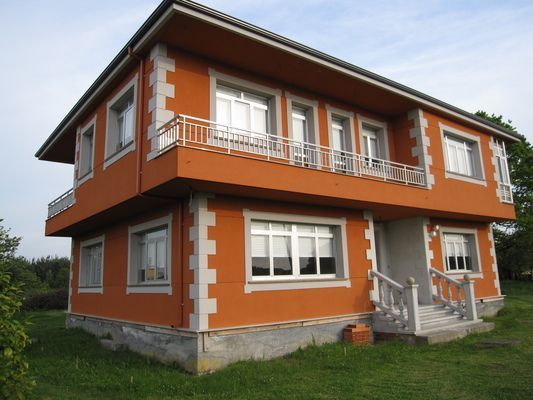 Una casa grande de color naranja con balcón y escaleras.