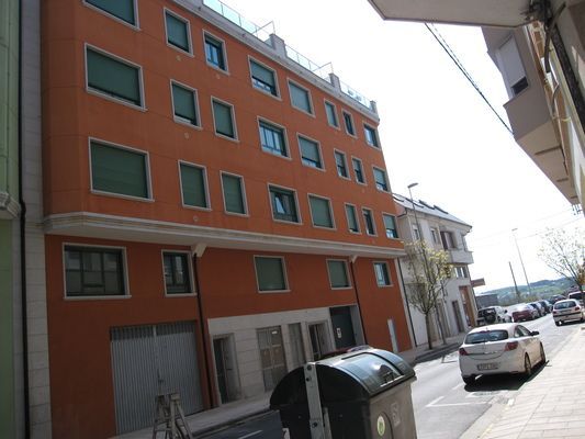 Un edificio con muchas ventanas y un bote de basura enfrente.