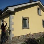 Una mujer está parada frente a una casa amarilla.