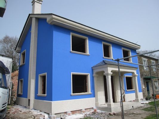 Una casa azul con molduras blancas está en construcción.