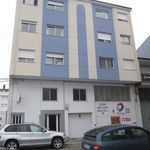 Un edificio con muchas ventanas y coches aparcados delante de él.