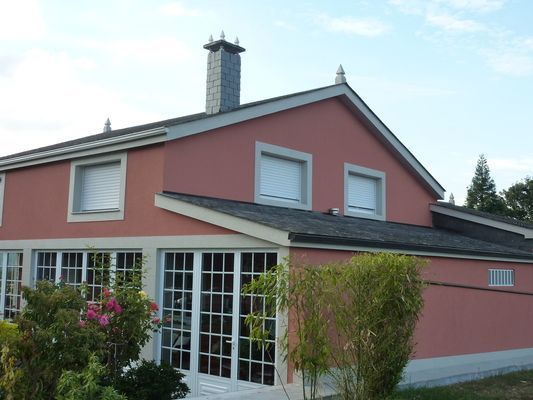 Una casa rosa con chimenea y muchas ventanas.