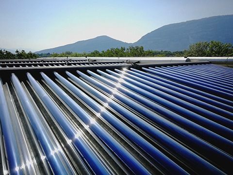 Panneaux solaires thermiques réfléchissant la lumière du soleil, avec des montagnes en arrière-plan.