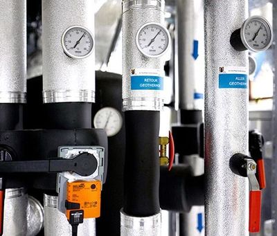 Tuyaux industriels avec manomètres et poignées de vannes colorées dans une salle des machines