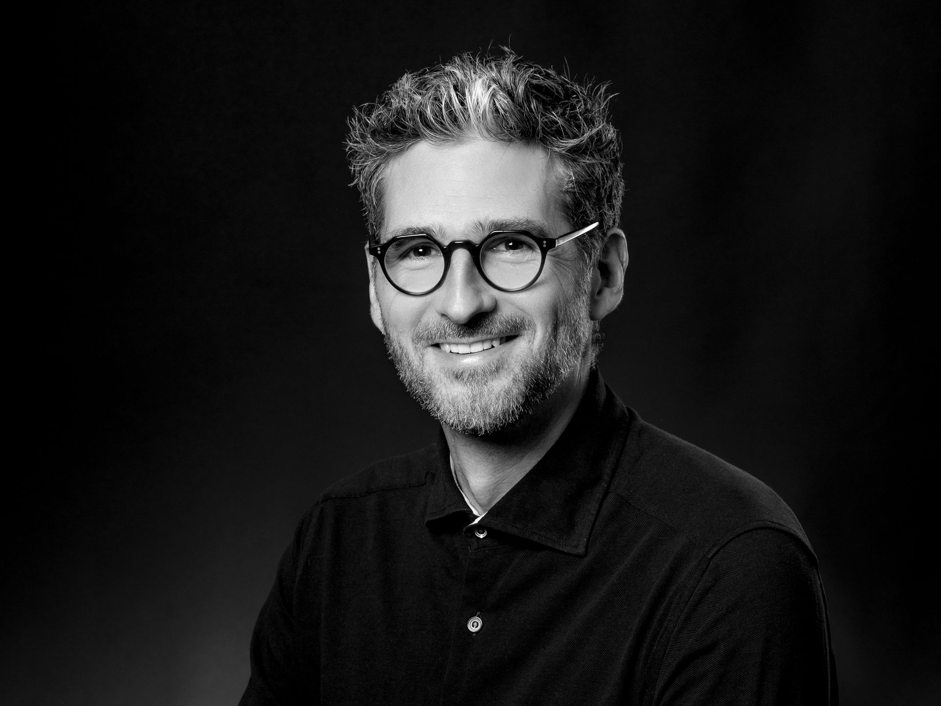 Photo en noir et blanc d'un homme souriant avec des lunettes