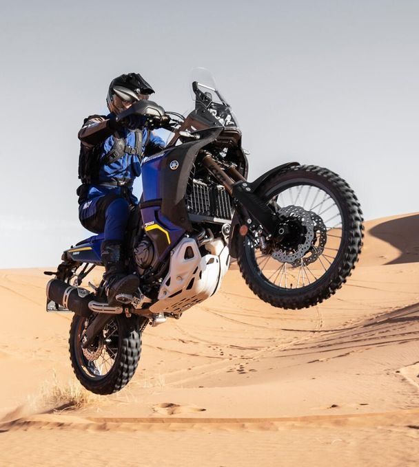 Un hombre conduce una motocicleta todoterreno en el desierto.