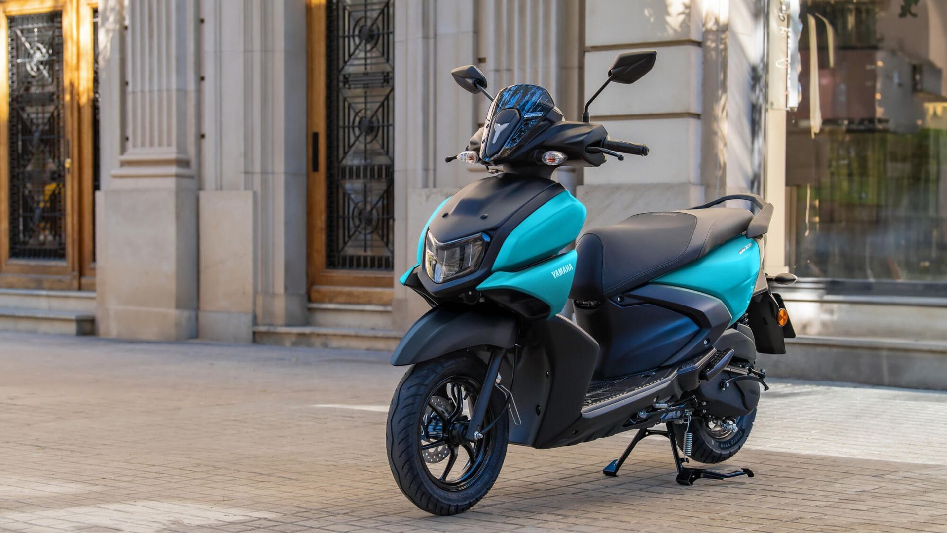 Un scooter azul y negro está estacionado frente a un edificio.
