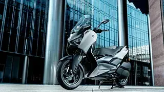 Un scooter blanco está estacionado frente a un edificio.