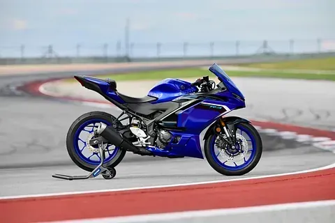 Una motocicleta azul está estacionada al costado de una pista de carreras.